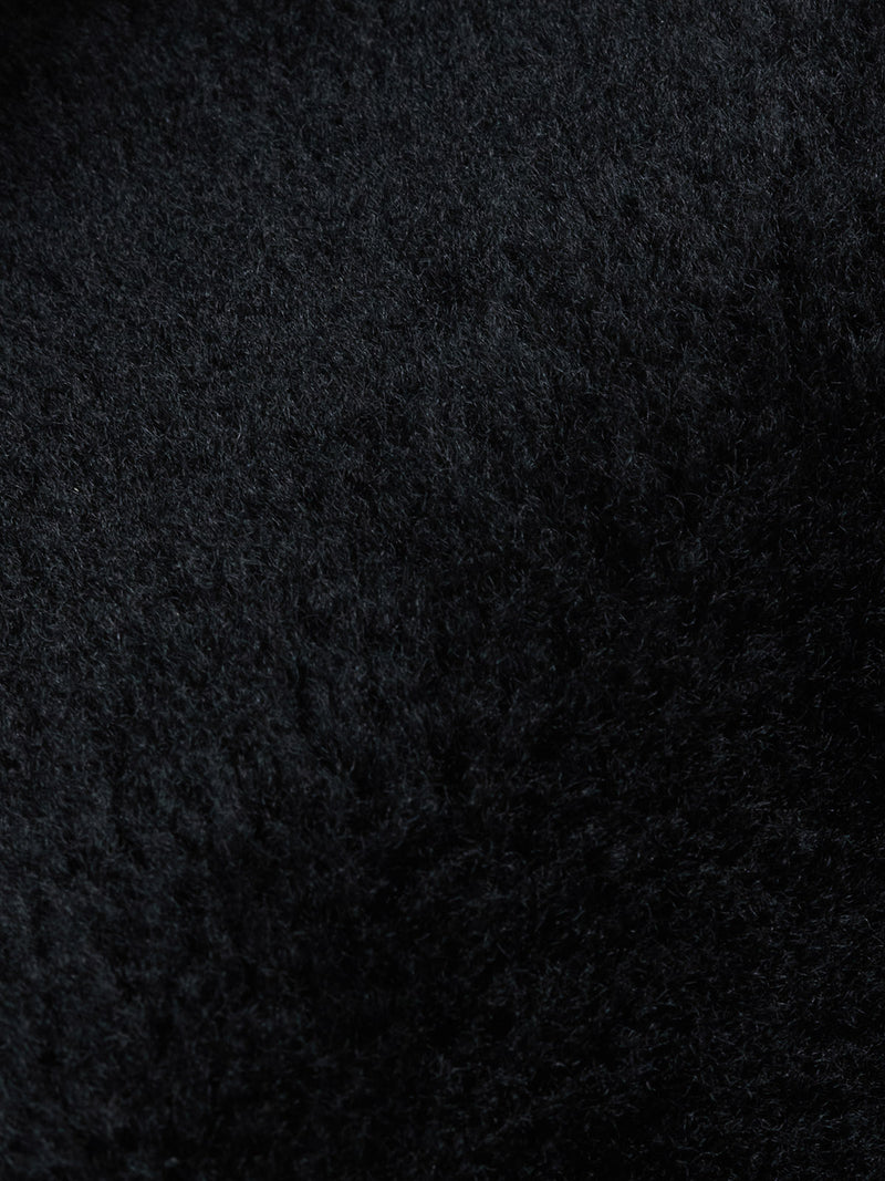 Close-up of the textured black surface of the Rufo Shearling Jacket - Scarab by Blue de Gênes, featuring soft, dense sheepskin with subtle shading and a wavy pattern—evoking the luxury of genuine shearling.