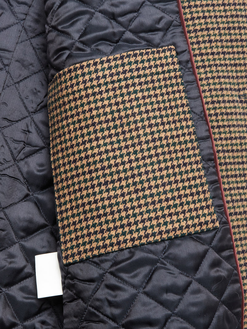 Close-up of the Blue de Gênes Massone Check Coat - Multi Check, featuring quilted black diamond-stitched lining, houndstooth brown and black Melton wool, and a partially visible white blank clothing tag near the edge.