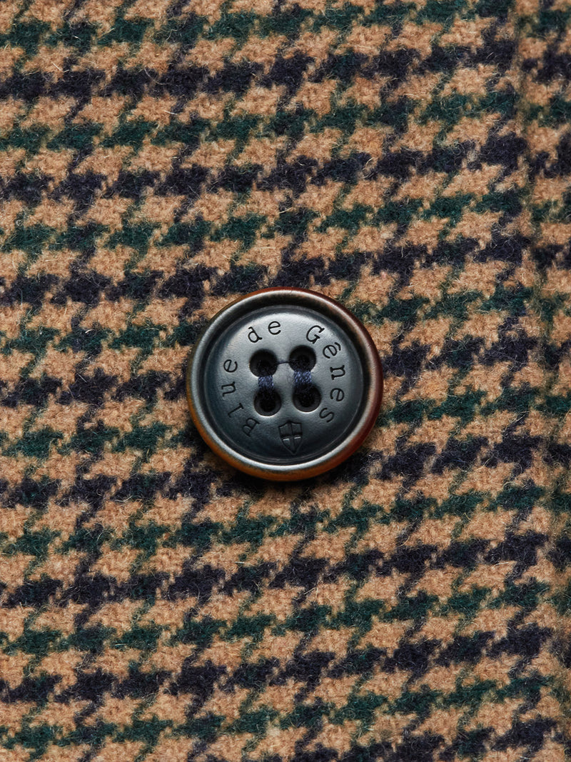 Close-up of a dark button inscribed with Blue de Gênes, sewn onto brown and dark green houndstooth Italian wool fabric of the Massone Check Coat - Multi Check.