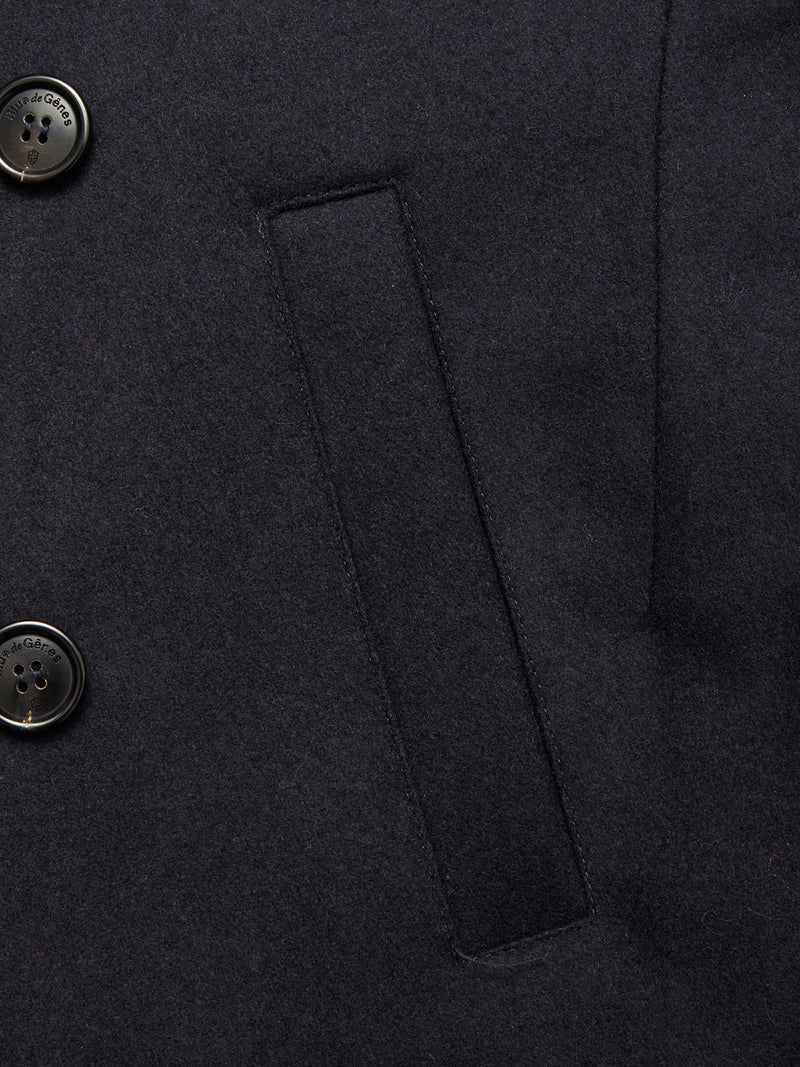 Close-up of the Shiba Melton Coat - Dark Navy by Blue de Gênes reveals two black buttons on the left, a central welt pocket, and fine stitching on smooth Italian Melton wool.
