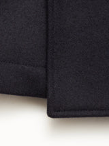 Close-up of the corner of the Blue de Gênes Shiba Melton Coat in Dark Navy, showcasing its thick Italian Melton wool, precise stitching, and sharp edges against a light background.