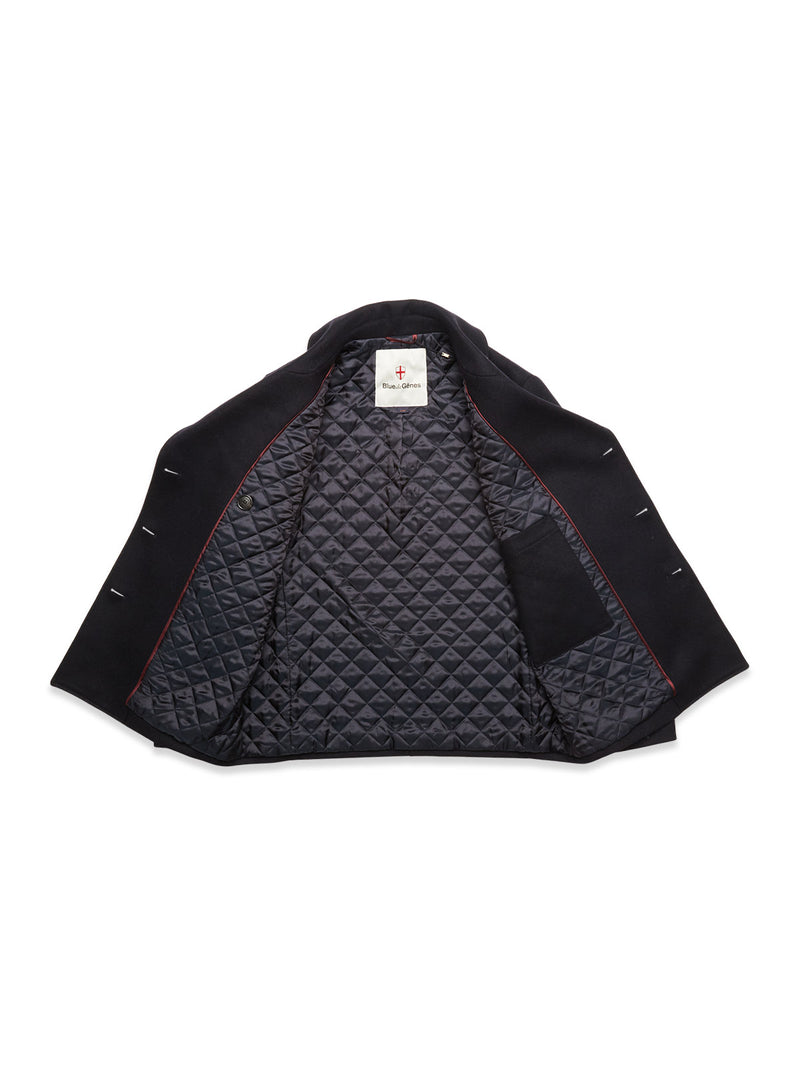 A Blue de Gênes Shiba Melton Coat in dark navy is shown open, displaying its quilted diamond-pattern lining, an inner left pocket, and a neck tag with red text that highlights the quality Italian Melton wool.