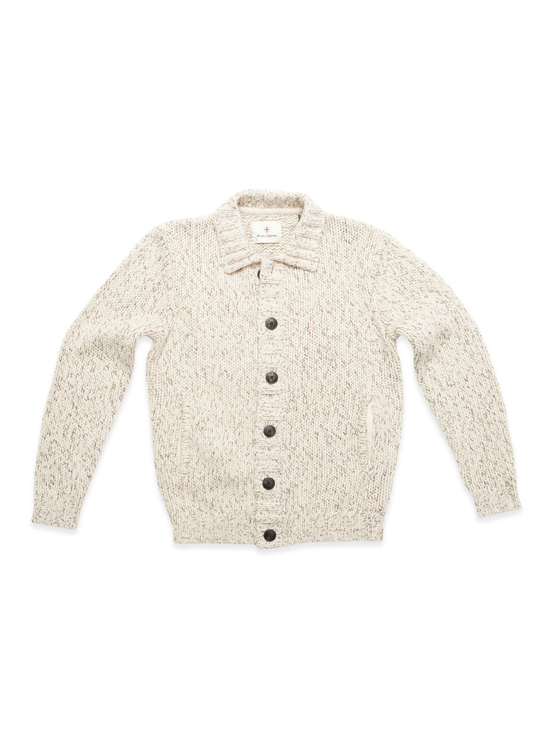 The Blue de Gênes Sakura Knit Cardigan in Stone is a cream chunky knit sweater with long sleeves, front pockets, and large dark buttons, pictured laid flat on a white background.