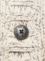 Close-up of the chunky knit cream and gray fabric from the Sakura Knit Cardigan - Stone by Blue de Gênes, showcasing a black button engraved with the brand name and a small shield emblem.