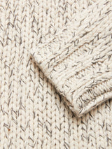 Close-up of the Sakura Knit Cardigan - Stone by Blue de Gênes, a cream chunky wool blend with gray flecks and a folded sleeve—showcasing its cozy texture, perfect for layering.