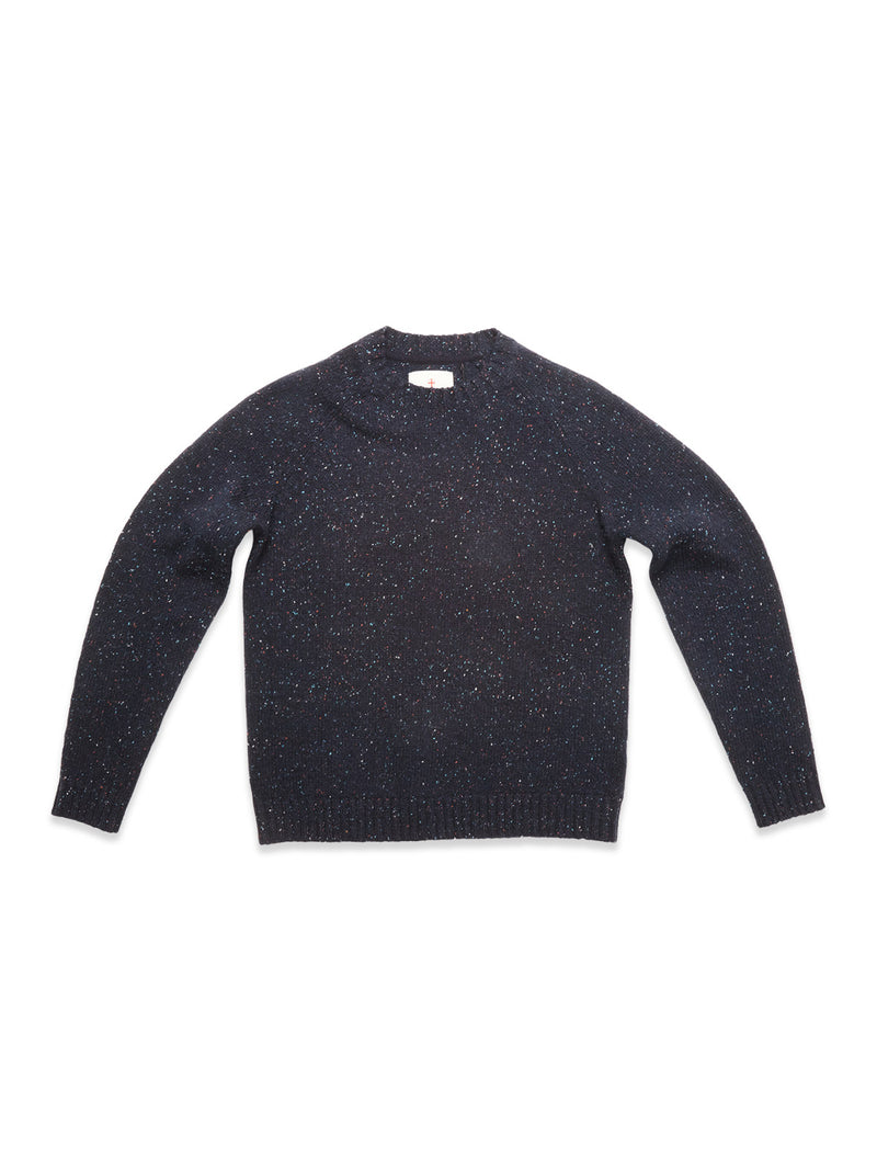 The Blue de Gênes Honshu Crewneck Knit in navy is a long-sleeve, lambswool blend sweater with multicolored speckles, shown laid flat on a white background.