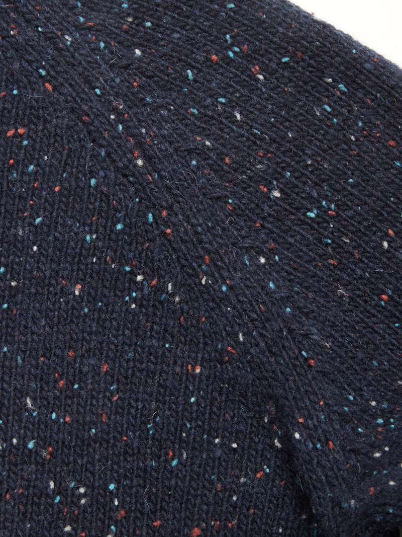 Close-up of the Honshu Crewneck Knit in Navy by Blue de Gênes, showing the chunky lambswool blend with a speckled pattern of red, white, and blue flecks. The knit’s texture and stitching are clearly visible.