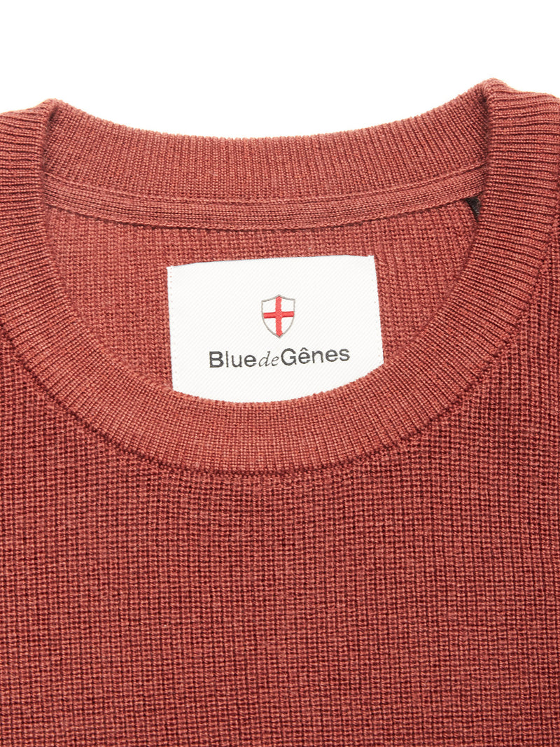 Close-up of the Porto Knit - Henna crewneck sweater by Blue de Gênes, featuring a white brand label and red and white shield emblem—a refined piece for any menswear collection.