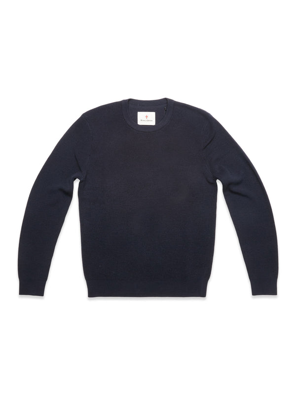 The Blue de Gênes Porto Knit in navy is a classic men's wool crewneck sweater, shown laid flat on a white background with a small white tag at the neckline.