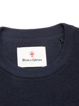 Close-up of the Porto Knit - Navy crewneck sweater by Blue de Gênes, featuring a white label with the brand name and red shield logo inside the collar—a stylish addition to your menswear collection.