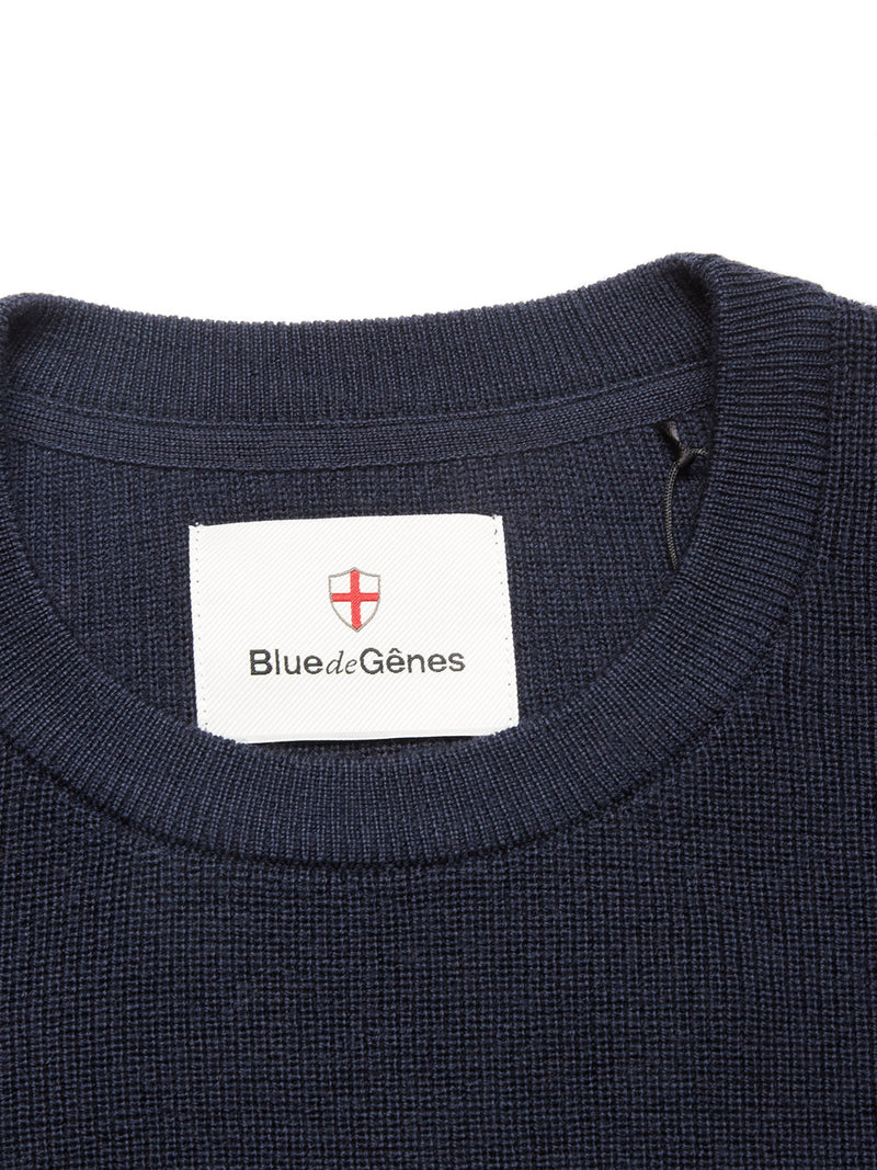 Close-up of the Porto Knit - Navy crewneck sweater by Blue de Gênes, featuring a white label with the brand name and red shield logo inside the collar—a stylish addition to your menswear collection.