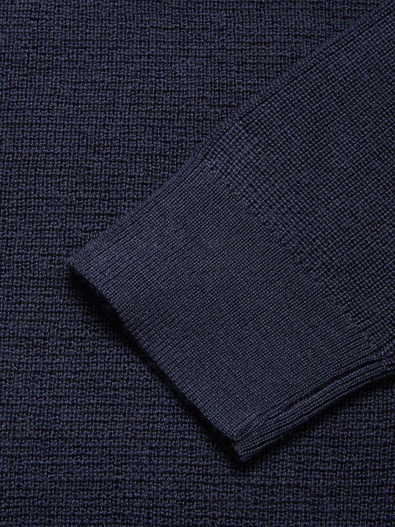 Close-up of the Porto Knit - Navy by Blue de Gênes, highlighting the detailed textured wool weave and the cuff of this long-sleeved menswear crewneck sweater.