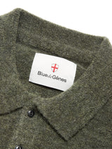 Close-up of the textured collar and corozo buttons on the Malakka Polo Knit - Army by Blue de Gênes. The inside label displays Blue de Gênes with a red cross emblem on a white background.