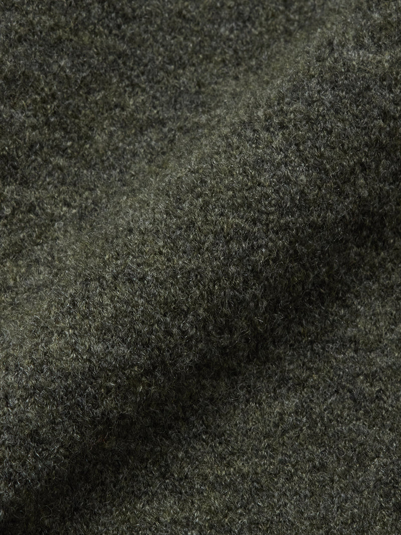 Close-up of Blue de Gênes' Malakka Polo Knit - Army, a textured dark green wool fabric with a soft, fuzzy surface, visible fibers, gentle folds, and a subtly heathered look.