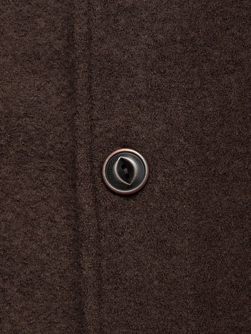 Close-up of the Blue de Gênes Kojima Wool Jacket - Chocolate, showing the textured brown boiled wool fabric and a single glossy, dark-centered button fastened through the buttonhole.