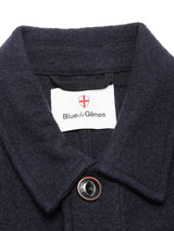 Close-up of the collar and top button on the Kojima Wool Jacket - Navy by Blue de Gênes, with a white label inside the collar showing the brand name below a red and white shield emblem.