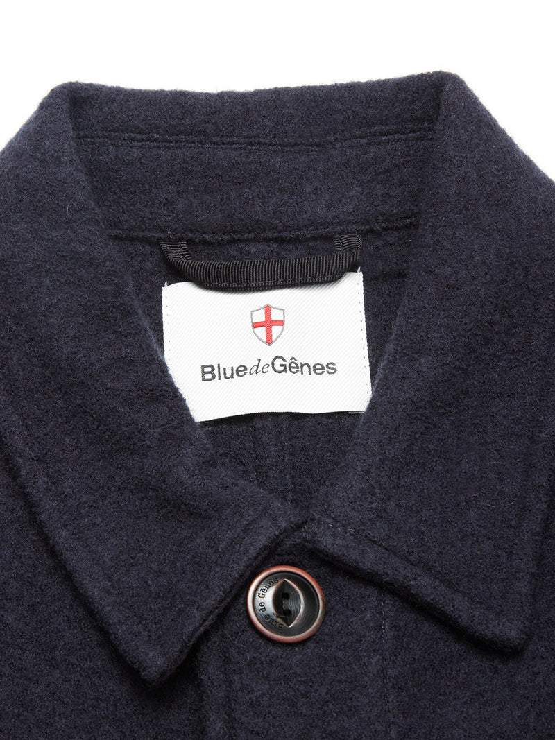Close-up of the collar and top button on the Kojima Wool Jacket - Navy by Blue de Gênes, with a white label inside the collar showing the brand name below a red and white shield emblem.