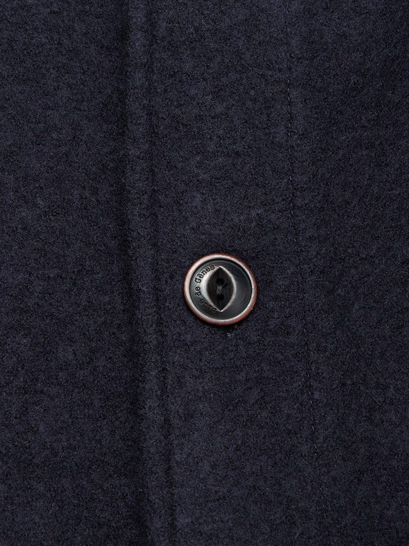 Close-up of a black button on the Blue de Gênes Kojima Wool Jacket - Navy, showing detailed stitching and the textured navy boiled wool fabric.