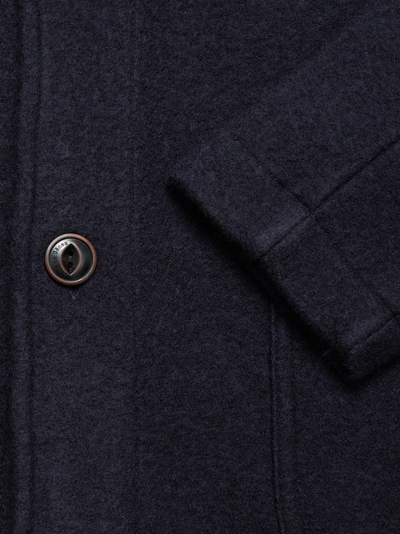 Close-up of the Blue de Gênes Kojima Wool Jacket - Navy, showing its textured boiled wool fabric, single brown button, and part of a pocket with visible stitching.