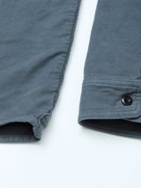 Close-up of the cuffs on a Blue de Gênes Nagano Overshirt - Dark Slate in cotton moleskin, with a black button, visible stitching, and soft fabric against a light background.