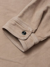A close-up of the Blue de Gênes Nagano Overshirt - Fungi shows its soft beige cotton moleskin cuff, finished with a black button and displayed flat on a matching surface.