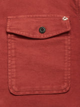 Close-up of the pocket on the Blue de Gênes Nagano Overshirt in Henna, featuring rust-colored moleskin cotton, a buttoned flap, and a small stitched white detail on the upper right corner of the flap.