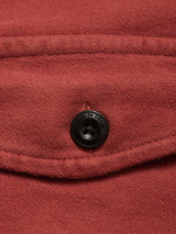 Close-up of the Blue de Gênes Nagano Overshirt in Henna, featuring red garment-dyed Moleskin cotton, a flap detail, and a black button engraved with the brand name.
