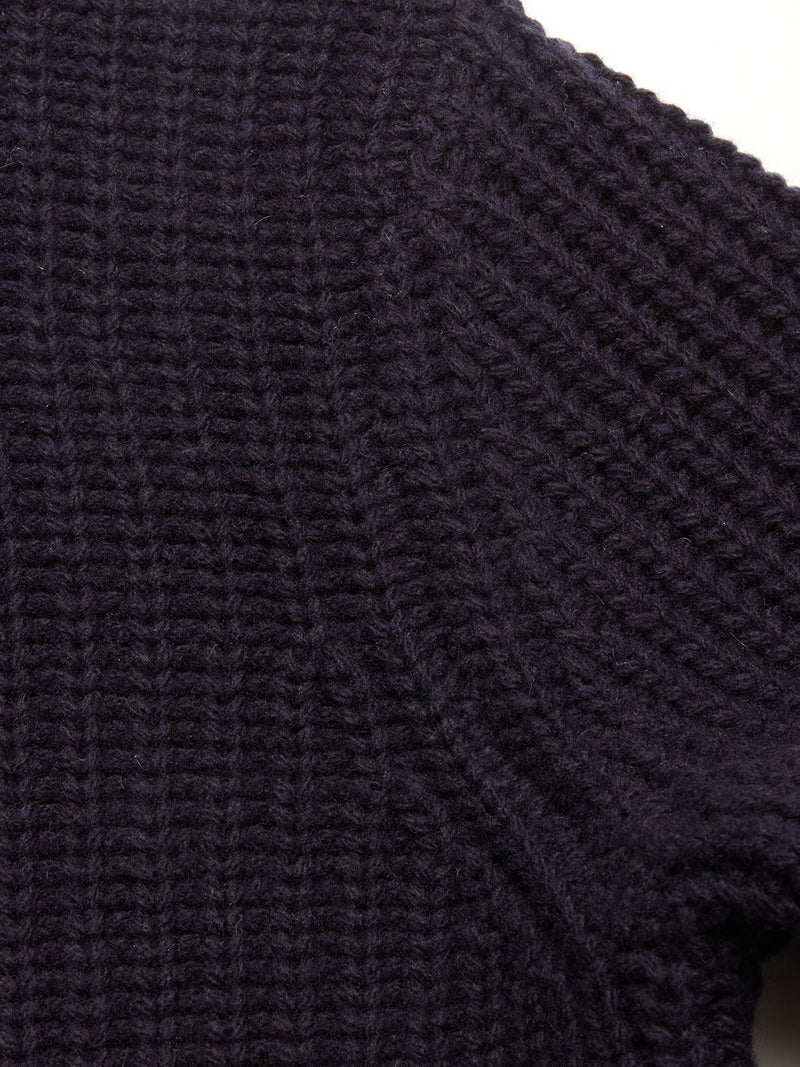 Close-up of the Yomaha Halfzip Knit in navy by Blue de Gênes, highlighting the chunky textured knit and wool blend fabric near the shoulder seam against a light background.
