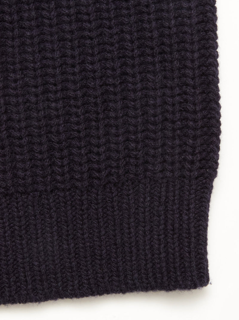 Close-up of the dark, ribbed wool blend fabric from the Blue de Gênes Yomaha Halfzip Knit in navy. The chunky knit texture and pattern are clearly visible against a light background.