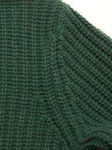 Close-up of the Yomaha Halfzip Knit - Scarab by Blue de Gênes, featuring dark green chunky ribbed knit with detailed stitching. The soft, thick wool blend suggests a cozy sweater ideal for cold weather.