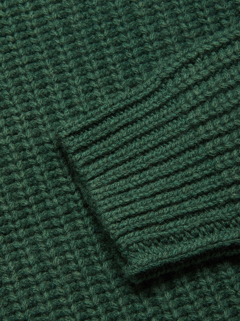 Close-up of the Yomaha Halfzip Knit - Scarab by Blue de Gênes, featuring a textured ribbed pattern in chunky green knit with a diagonal sleeve cuff detail.