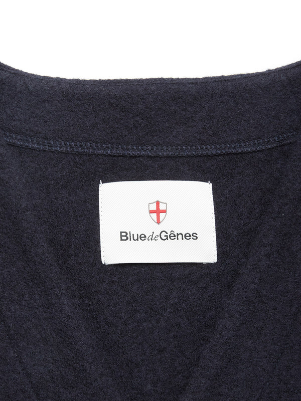Close-up of the Koi Wool Gilet - Navy by Blue de Gênes, featuring a classic design with a dark blue boiled wool fabric and a white label under the brand's red and white shield logo.