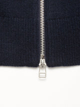 Close-up of the silver zipper on the Blue de Gênes Nuvali Polo Cardigan in Navy, partially unzipped on ribbed knit fabric, with the slider and pull tab centered at the bottom.