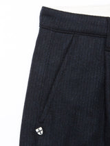 Close-up of the upper section of the Blue de Gênes Kibishi Solid Pant in Dark Navy, featuring an Italian wool blend, waistband, belt loop, pleat, and a small shield-shaped pin near the pocket.