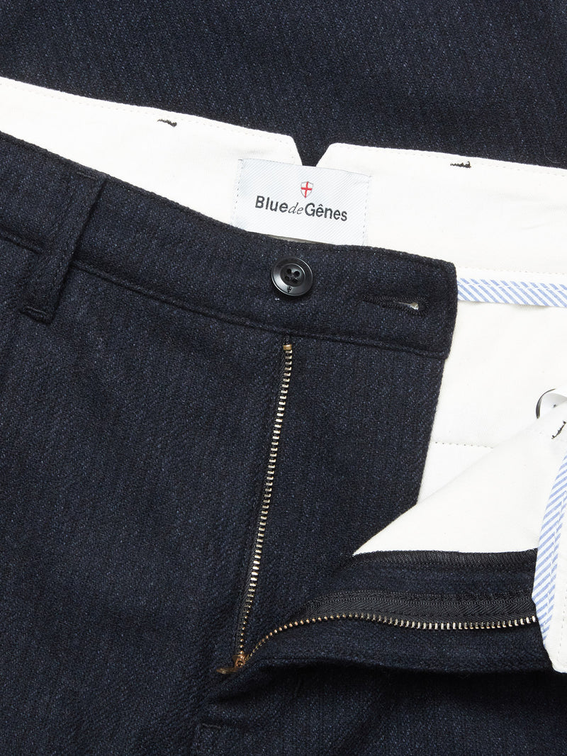 Close-up of the Kibishi Solid Pant - Dark Navy by Blue de Gênes, highlighting the waistband and fly with zipper and button closure, a white inner lining, and the Blue de Gênes label.