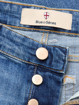 Close-up of Vinci Girisha Used Jeans by Blue de Gênes in comfort stretch denim, featuring visible stitching, metal shield-embossed buttons, and a beige brand label with a red and white shield logo.