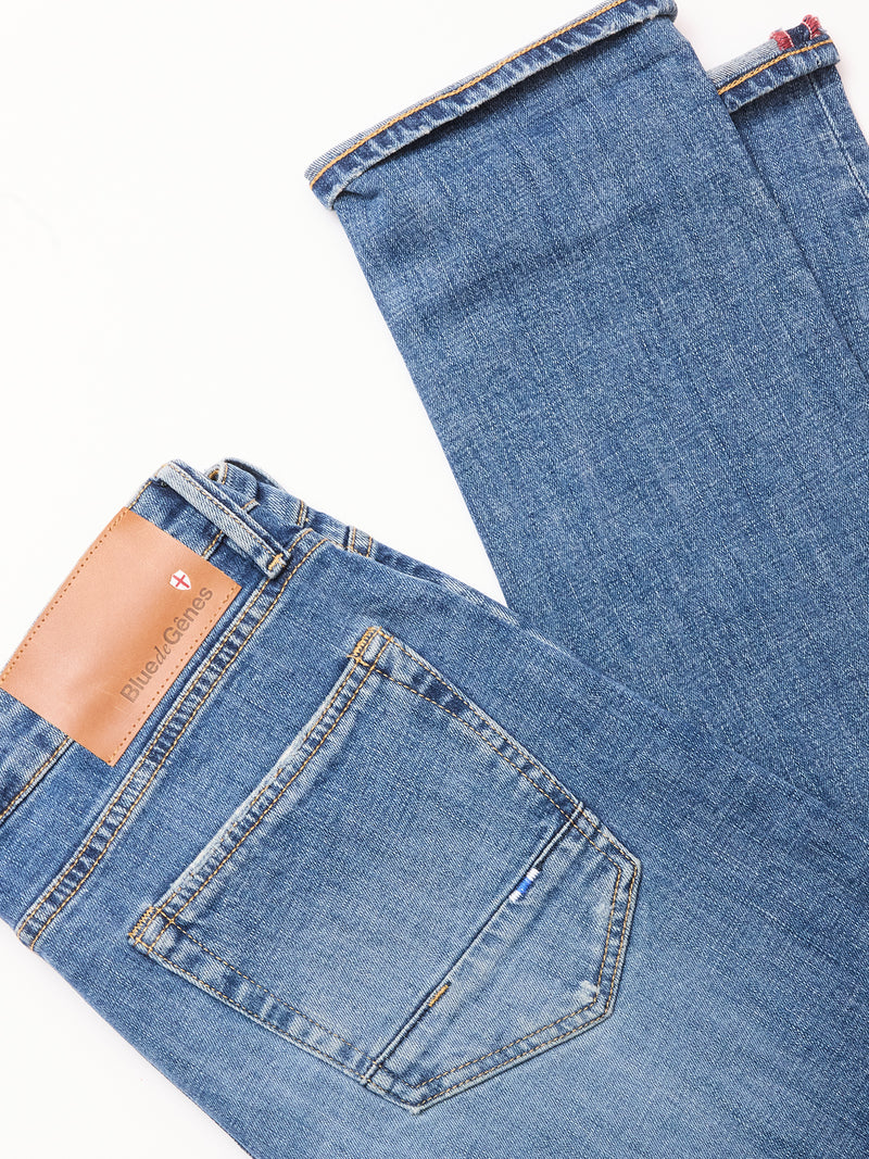 Blue de Gênes Vinci Girisha Used Jeans in blue comfort stretch denim are laid flat on a white background, highlighting the back pocket and a tan branded leather patch on the waistband.