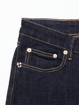 Close-up of the upper front section of Blue de Gênes Vinci Girisha Rinse Jeans, Rinse Wash, with a small coin pocket, tan stitching, metal rivets, and a shield-shaped patch with a red cross on white.