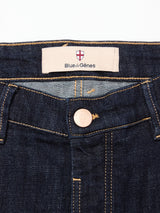 Close-up of the waistband on Blue de Gênes Vinci Girisha Rinse Jeans in rinse wash, showing comfort stretch dark blue denim, a metal button, and a sewn Blue de Gênes label below the red and white shield logo.