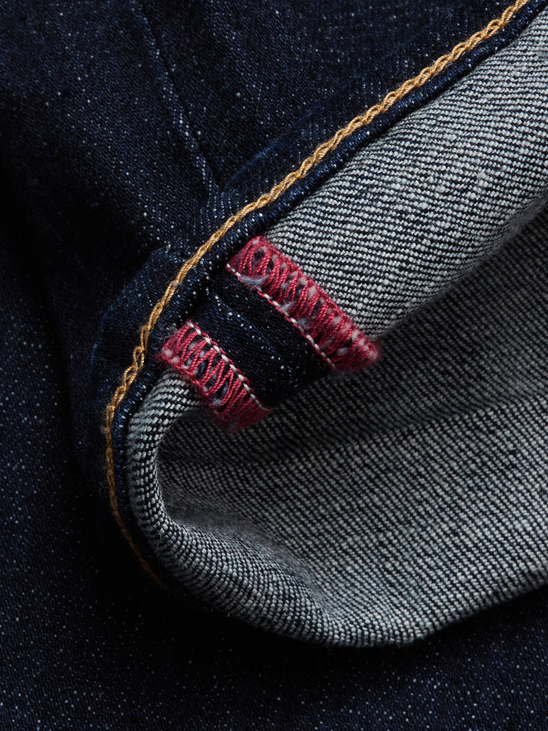 Close-up of Blue de Gênes Vinci Girisha Rinse Jeans in rinse wash, showcasing the turned-up hem with red stitching, yellow thread on the edge, and visible fabric texture highlighting five-pocket construction details.