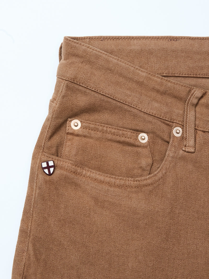 Close-up of Blue de Gênes Vinci Iro Pant in chocolate comfort stretch twill, highlighting the waistband, belt loop, front pocket, and signature pin with a white and red cross shield—perfect for regular fit jeans enthusiasts.
