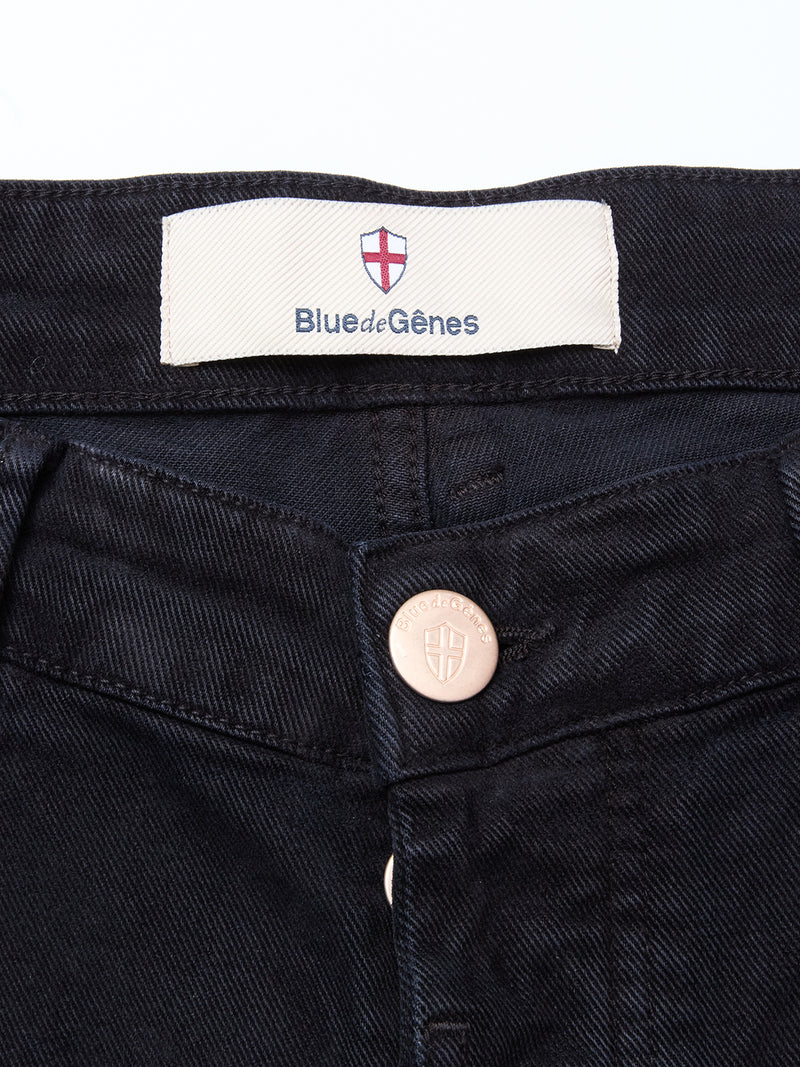 Close-up of the waistband of Vinci Iro Pant - Navy by Blue de Gênes, showing a label with a red and white shield logo and a metal button embossed with a crest. Made from comfort stretch twill for lasting comfort.