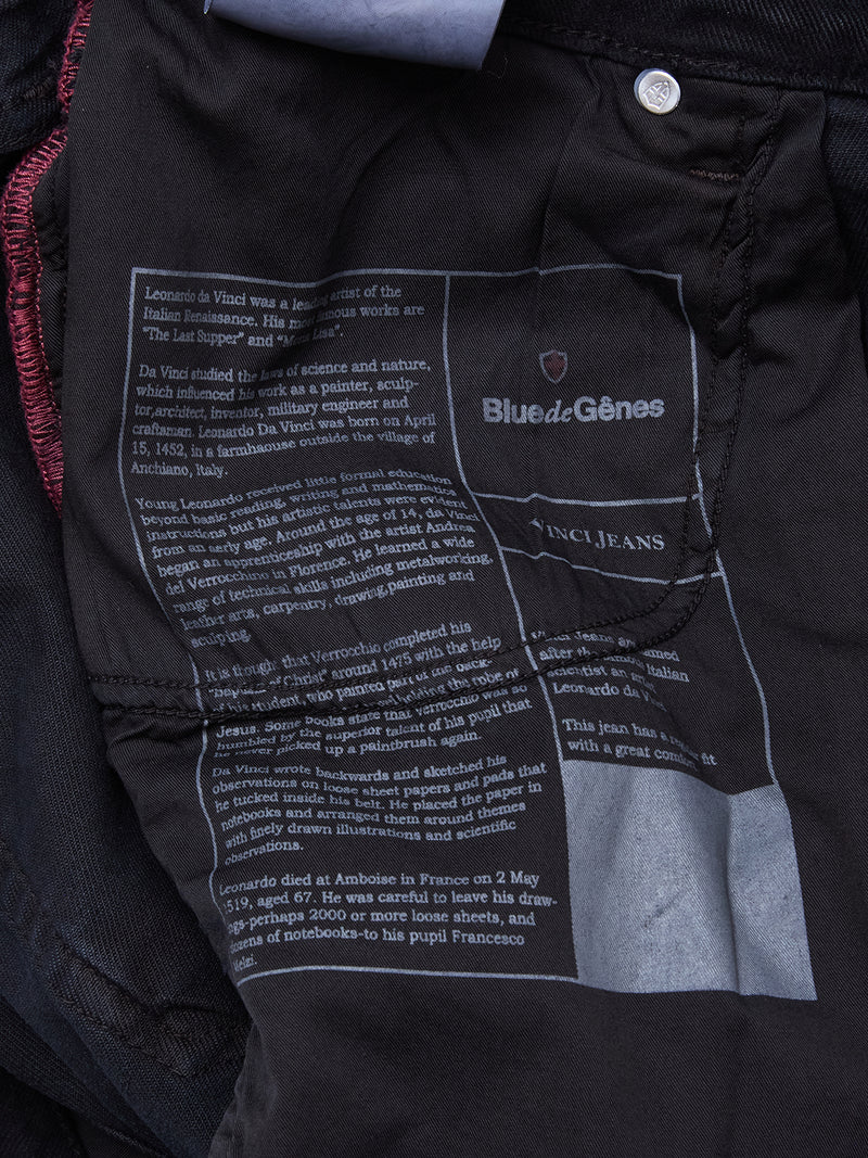 A close-up of the inside label of Blue de Gênes Vinci Iro Pant - Navy, showing printed brand details and text about Leonardo da Vinci on dark comfort stretch twill with visible stitching.