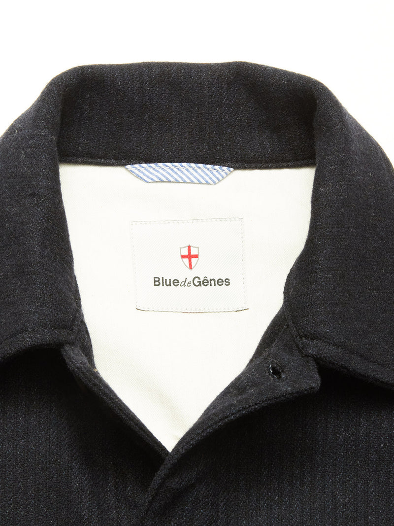Close-up of the Vincenzo Solid Jacket - Dark Navy by Blue de Gênes. The label displays the brand with a red and white shield logo, while the white inner lining features a blue-striped neck tag.