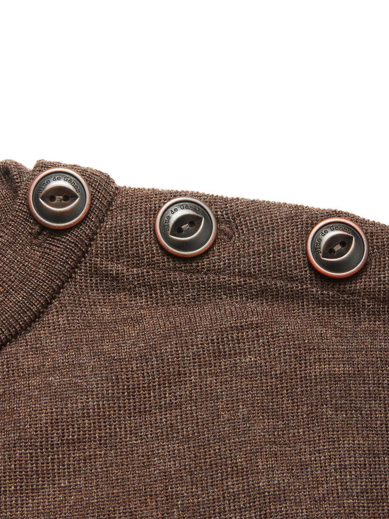 Close-up of the Toyama Knit L/S - Brown by Blue de Gênes, a Merino wool sweater featuring three black buttons with thin red borders and engraved text along the shoulder seam.