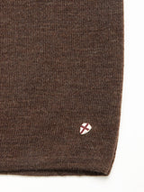Close-up of the Toyama Knit L/S in brown by Blue de Gênes, featuring a small white shield-shaped patch with a red cross emblem sewn near the edge.