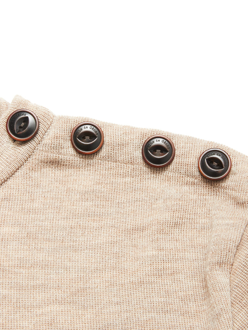 Close-up of the Blue de Gênes Toyama Knit L/S in oat, a beige sweater crafted from Merino wool with four dark brown buttons along the shoulder seam.
