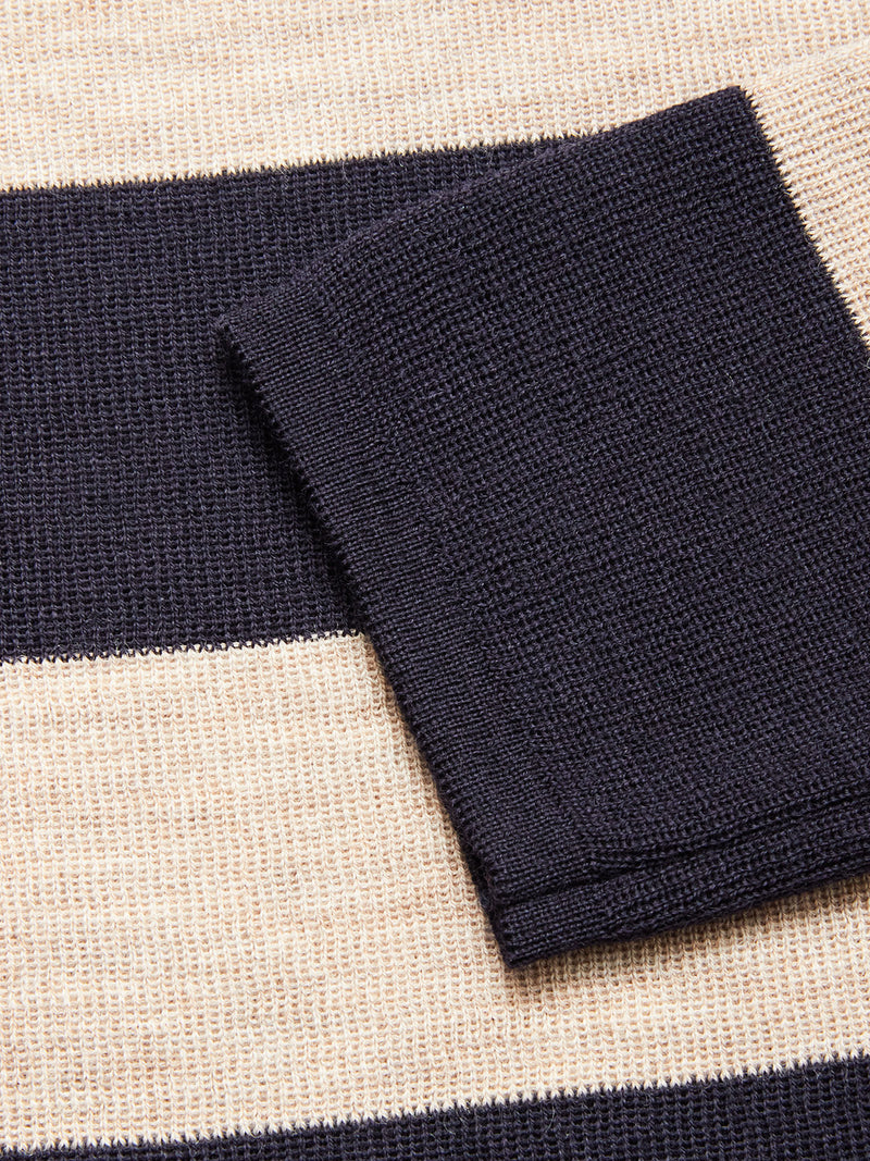 A close-up of the Blue de Gênes Toyama Stripe Knit L/S in Dark Navy highlights its cozy knit fabric, featuring navy and beige stripes with a folded section of the navy material on top.