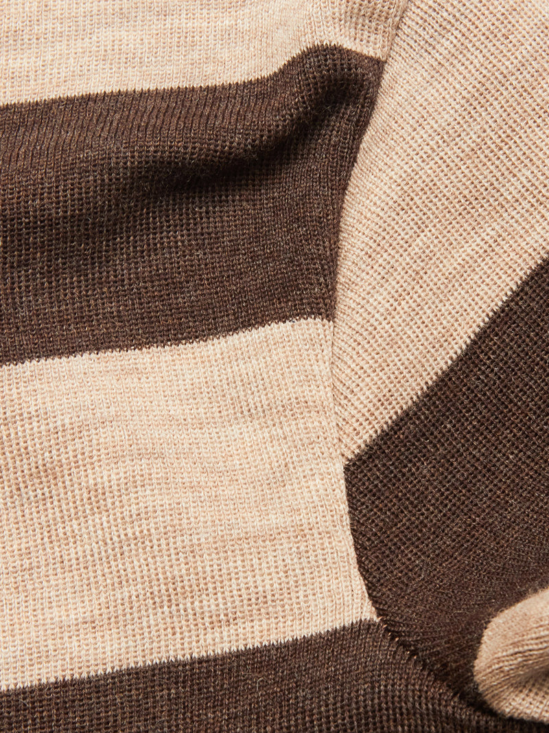Close-up of the Blue de Gênes Toyama Stripe Knit L/S - Oat, featuring wide horizontal beige and brown stripes. Cozy merino wool texture and subtle folds showcase its comfort and style.