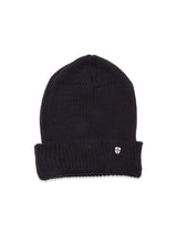The Boshi Beanie in dark navy by Blue de Gênes is rib-knitted in Denmark with a folded brim and features a small round metal shield emblem on the front.